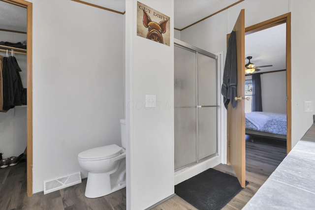 bathroom featuring walk in shower, toilet, wood-type flooring, ornamental molding, and ceiling fan