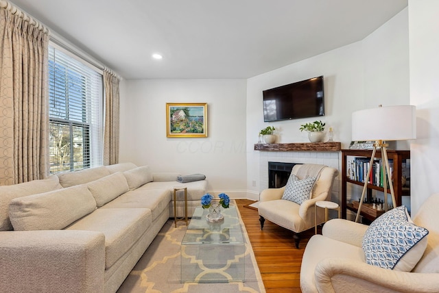 living room featuring a brick fireplace and wood-type flooring