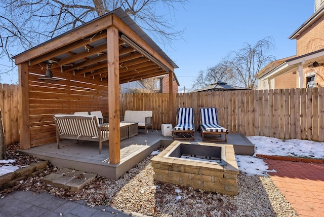 snow covered deck with an outdoor living space with a fire pit