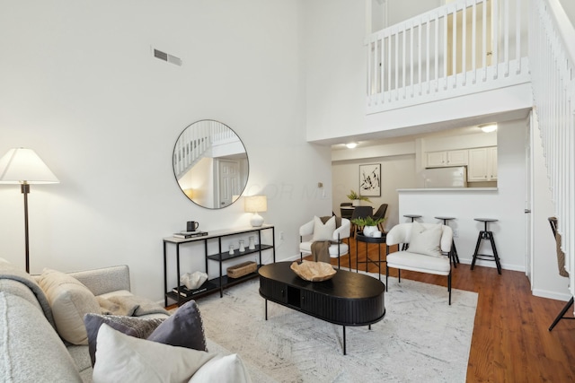 living room featuring a towering ceiling and dark hardwood / wood-style floors