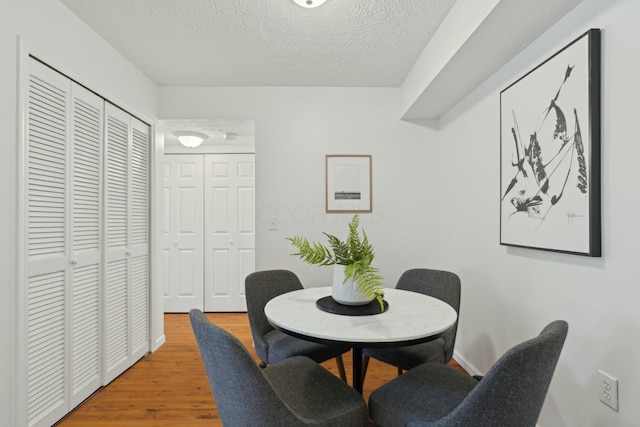 dining room with wood-type flooring and a textured ceiling