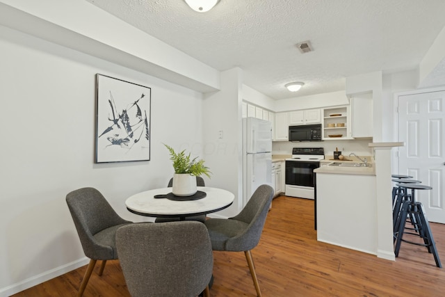 dining area featuring sink, hardwood / wood-style floors, and a textured ceiling