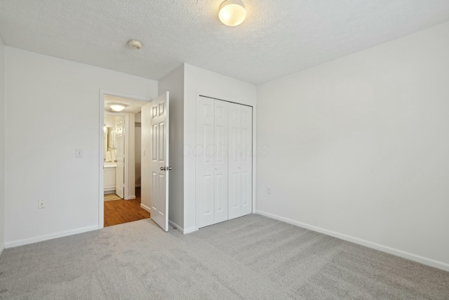 unfurnished bedroom with light colored carpet, a closet, and a textured ceiling