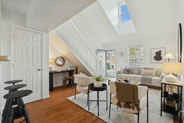 living room featuring a skylight, light hardwood / wood-style flooring, and high vaulted ceiling