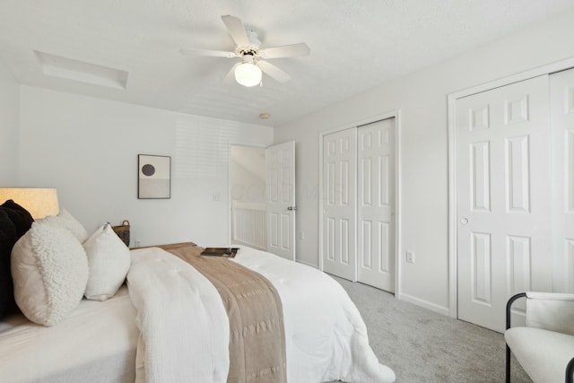 bedroom with two closets, light colored carpet, and ceiling fan