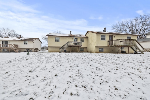 snow covered house featuring a wooden deck