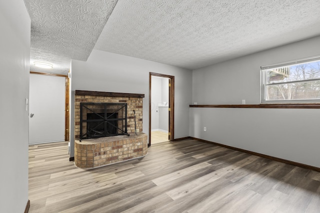 unfurnished living room featuring a fireplace, light hardwood / wood-style flooring, and a textured ceiling