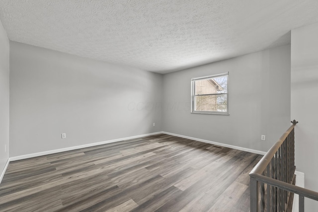 unfurnished room featuring a textured ceiling and dark hardwood / wood-style flooring