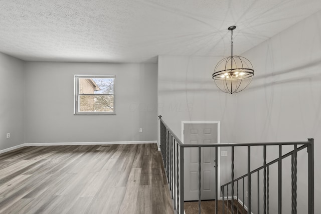 interior space with a textured ceiling, hardwood / wood-style flooring, and a chandelier