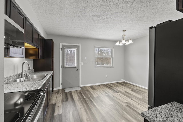 kitchen with decorative light fixtures, sink, range with electric cooktop, stainless steel refrigerator, and light hardwood / wood-style flooring