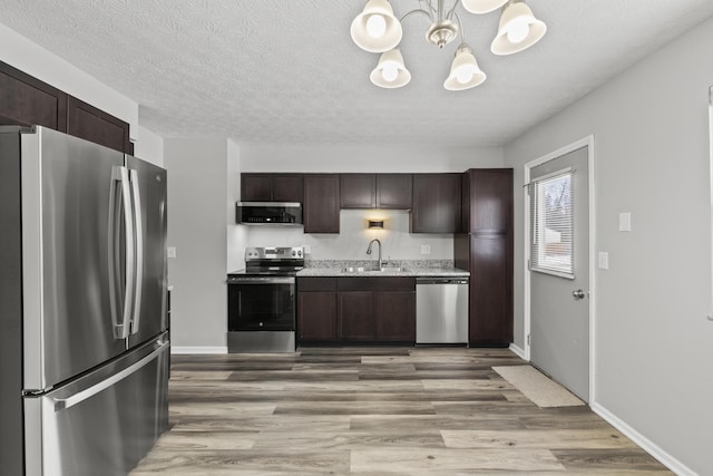 kitchen featuring sink, dark brown cabinetry, an inviting chandelier, and appliances with stainless steel finishes