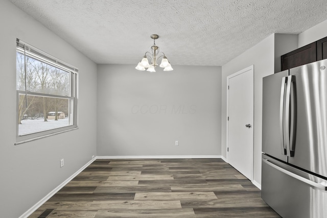 unfurnished dining area with a textured ceiling, dark hardwood / wood-style floors, and a notable chandelier