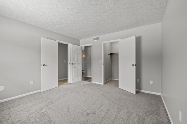 unfurnished bedroom with a closet, a textured ceiling, and light carpet