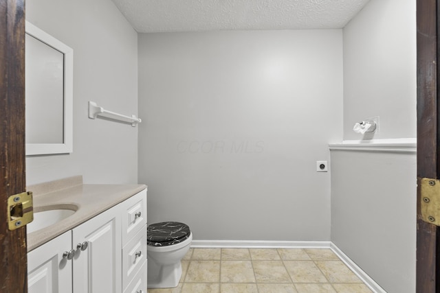 bathroom with vanity, toilet, and a textured ceiling