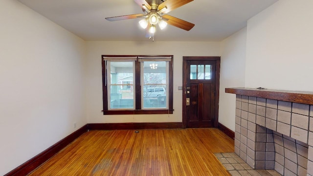 foyer entrance featuring ceiling fan, a tile fireplace, and light wood-type flooring