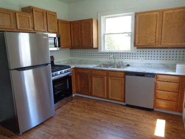 kitchen featuring tasteful backsplash, stainless steel appliances, sink, and light hardwood / wood-style flooring