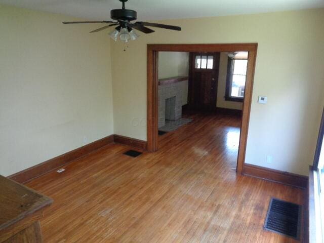 interior space featuring hardwood / wood-style floors, a brick fireplace, and ceiling fan