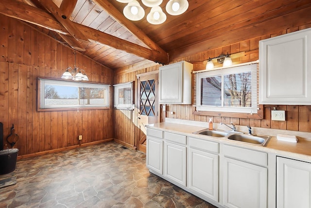 kitchen featuring pendant lighting, wood ceiling, white cabinetry, vaulted ceiling with beams, and sink