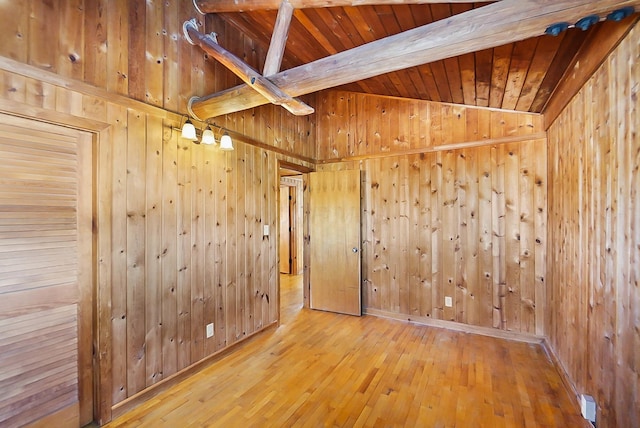 empty room with wood walls, beamed ceiling, and wood ceiling