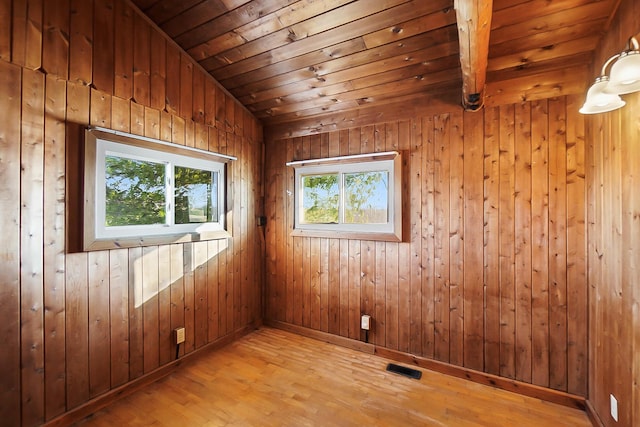 spare room with wooden walls, lofted ceiling, wood ceiling, and light wood-type flooring