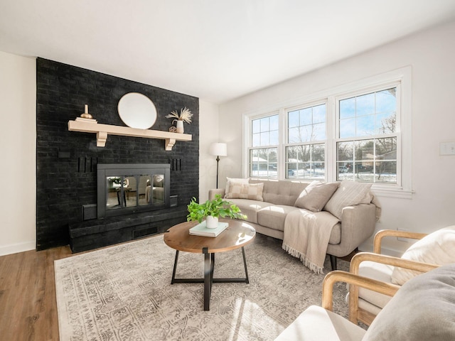 living room with hardwood / wood-style flooring and a brick fireplace