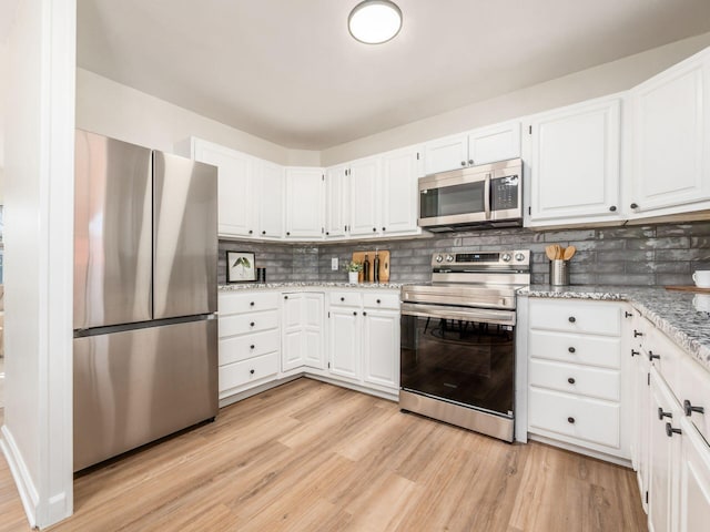 kitchen with white cabinets, decorative backsplash, light stone countertops, and appliances with stainless steel finishes