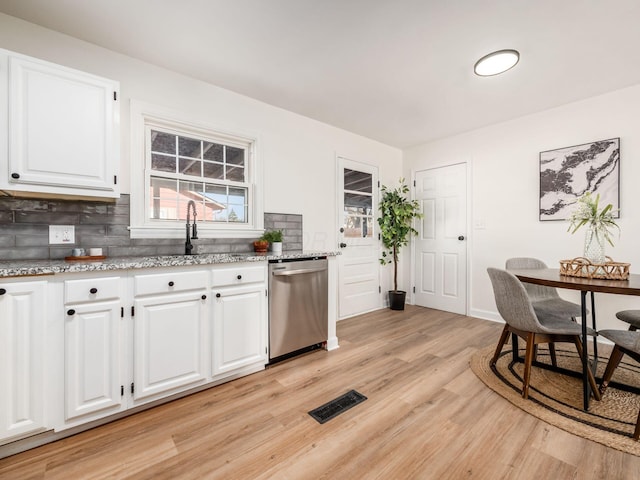 kitchen with stainless steel dishwasher, light hardwood / wood-style flooring, backsplash, white cabinets, and light stone countertops