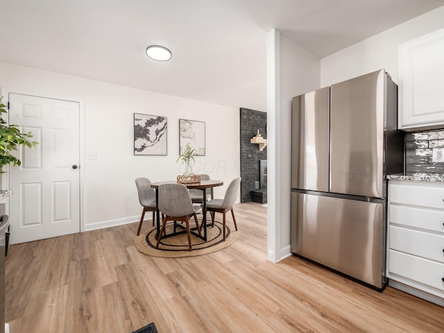 kitchen with light wood-type flooring, white cabinetry, decorative backsplash, and stainless steel fridge