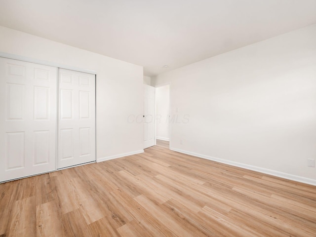 unfurnished bedroom with a closet and light hardwood / wood-style flooring