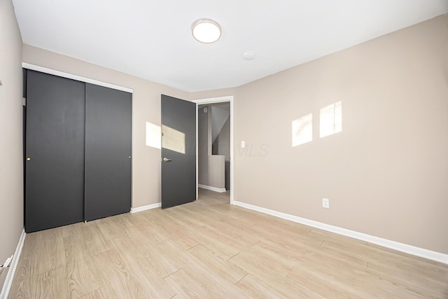 unfurnished bedroom with a closet and light hardwood / wood-style flooring