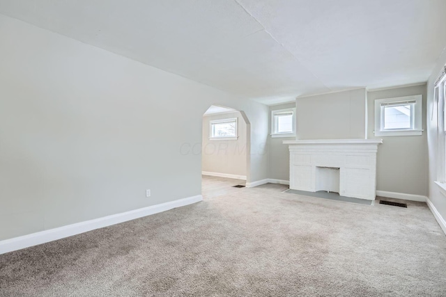 unfurnished living room featuring a wealth of natural light and light colored carpet