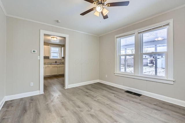 unfurnished room with crown molding, sink, ceiling fan, and light wood-type flooring