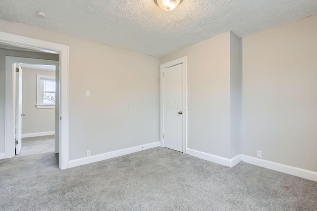 carpeted empty room with a textured ceiling