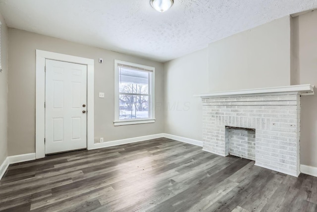 unfurnished living room featuring dark hardwood / wood-style flooring, a fireplace, and a textured ceiling