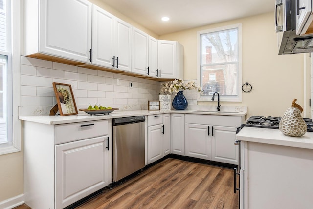 kitchen with dishwasher, sink, backsplash, dark wood-type flooring, and white cabinetry