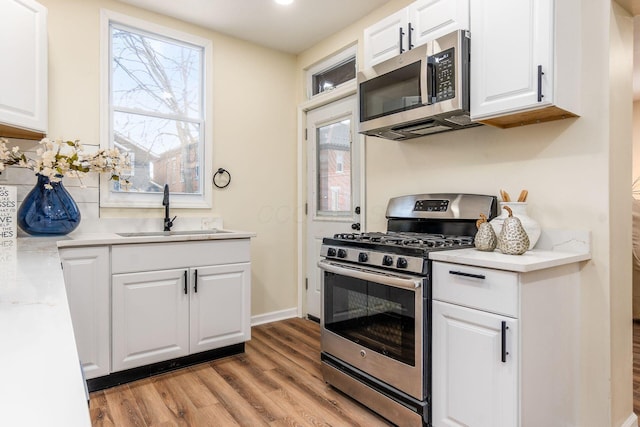 kitchen with sink, plenty of natural light, white cabinetry, light hardwood / wood-style floors, and stainless steel appliances