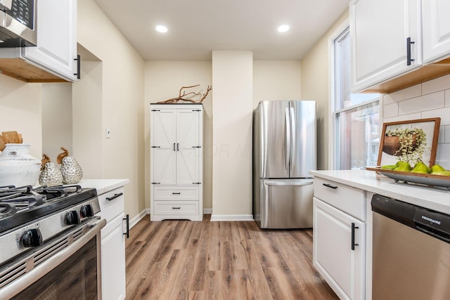 kitchen with white cabinets, stainless steel appliances, light hardwood / wood-style flooring, and tasteful backsplash