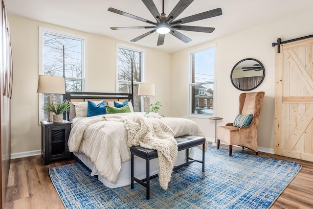 bedroom with ceiling fan, hardwood / wood-style floors, and a barn door