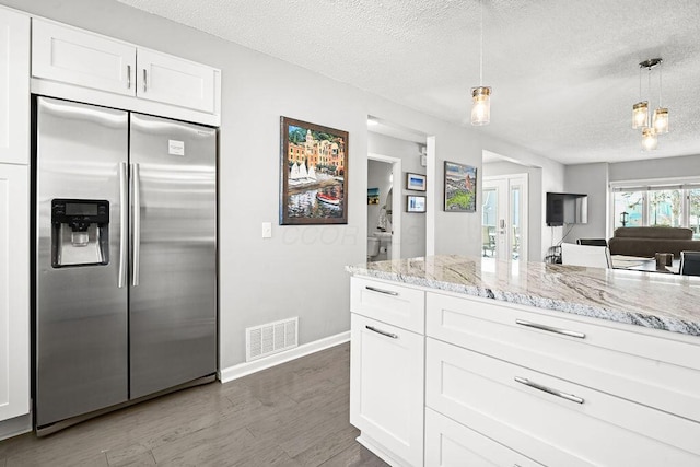 kitchen featuring stainless steel built in refrigerator, decorative light fixtures, a textured ceiling, and white cabinets