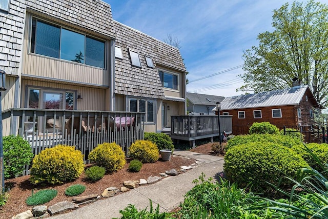 exterior space with a wooden deck and mansard roof