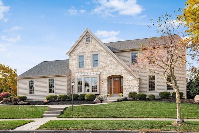 view of front of house with stone siding, roof with shingles, and a front lawn