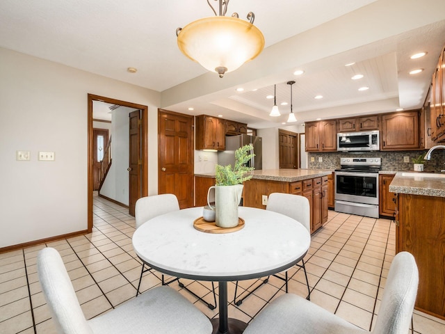 dining room with light tile patterned floors, baseboards, a raised ceiling, and recessed lighting