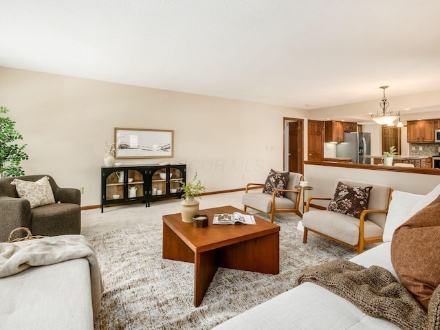 living area featuring light carpet and baseboards