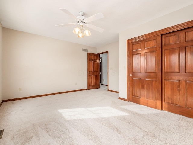 unfurnished bedroom with baseboards, visible vents, a ceiling fan, light colored carpet, and a closet