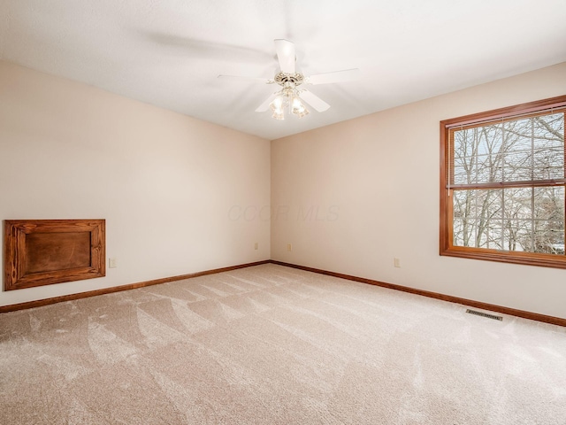 empty room featuring baseboards, visible vents, a ceiling fan, and light colored carpet