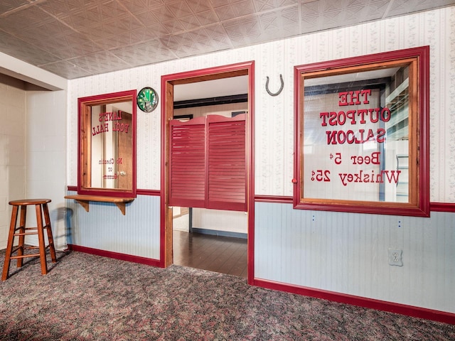 unfurnished room featuring an ornate ceiling, a wainscoted wall, carpet flooring, and wallpapered walls