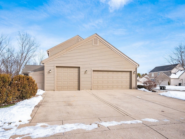 snow covered garage with concrete driveway