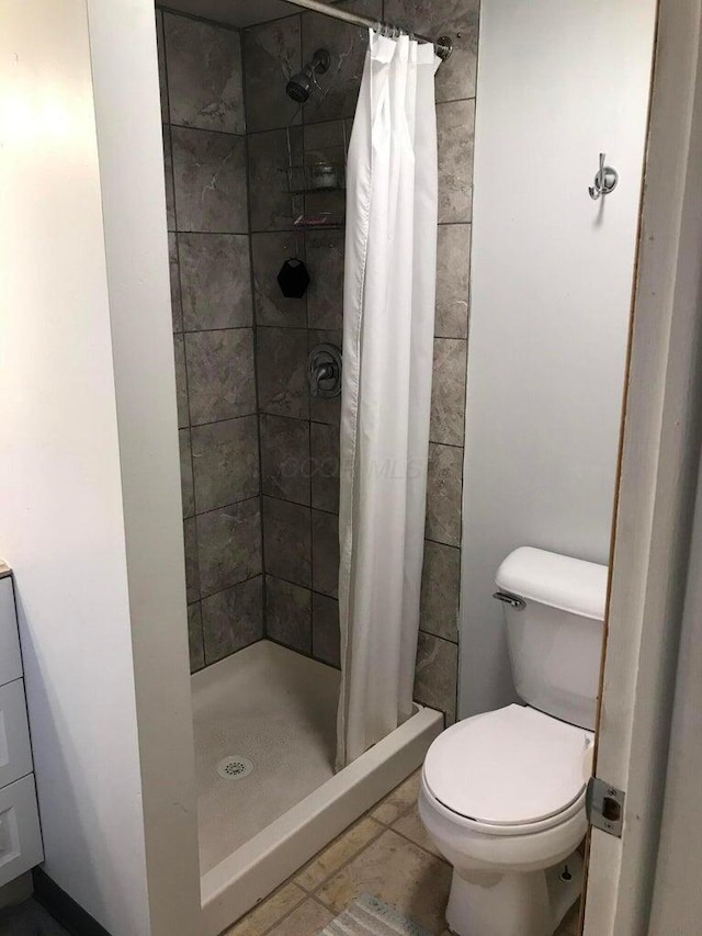 bathroom with toilet, tile patterned flooring, and a shower with shower curtain