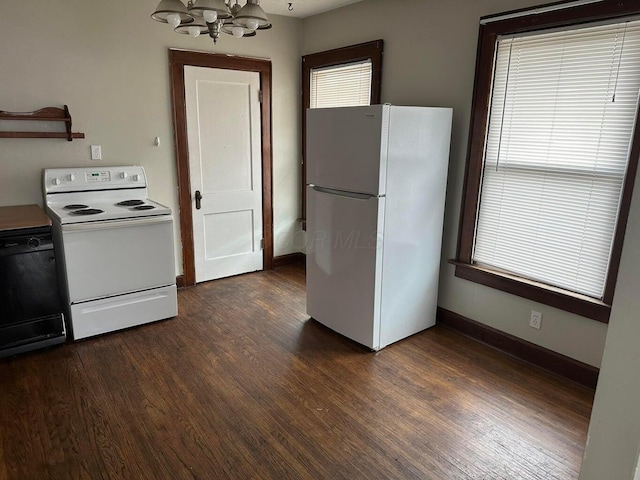 kitchen featuring white appliances, dark hardwood / wood-style floors, a wealth of natural light, and a notable chandelier