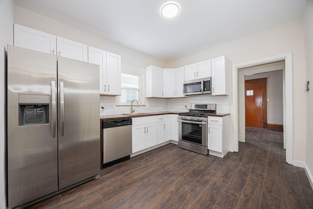 kitchen with appliances with stainless steel finishes, sink, white cabinets, and backsplash